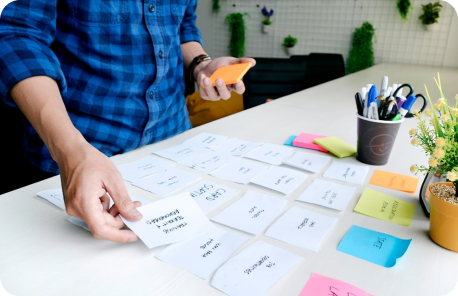 Product designer laying out sticky notes on a table with various subjects written on them