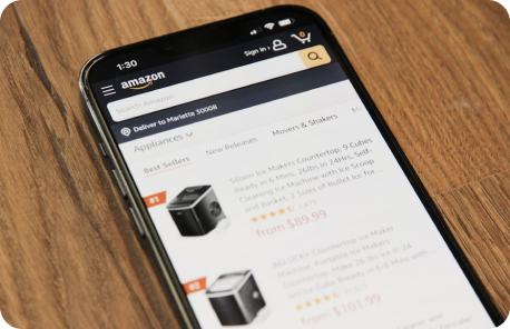 Mobile device placed on a table. On the screen is Amazon's mobile application. The user has done a product search for appliances and is viewing results.