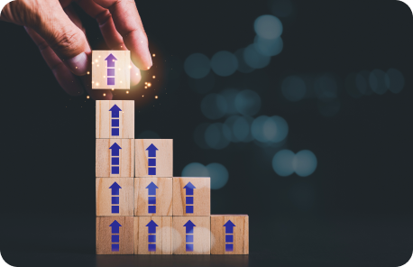 Hand stacking wood block objects into a staircase formation. Each box has an upward facing arrow painted onto it.d
