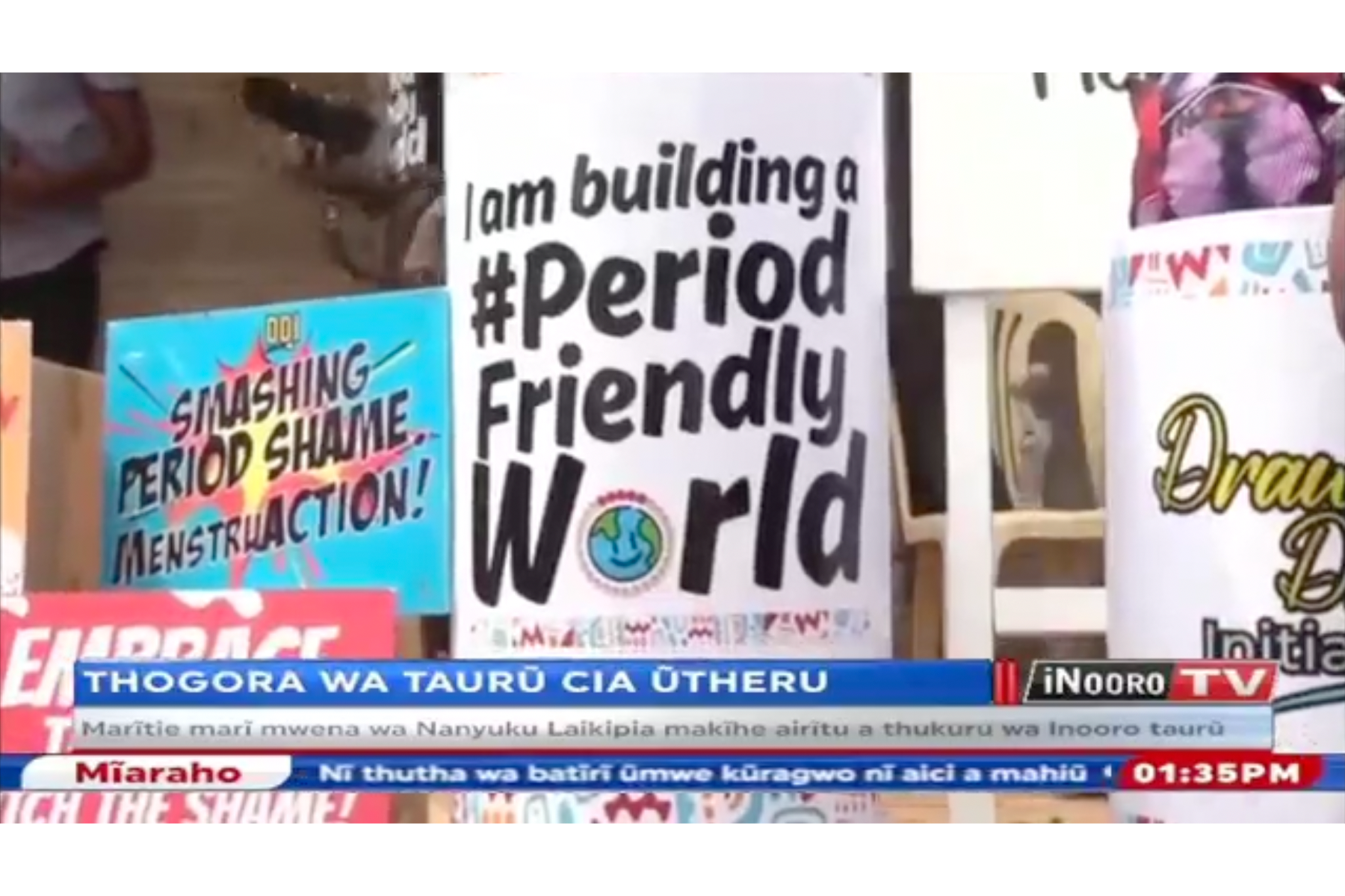 A screenshot of a TV show that shows a poster saying "I am building a #PeriodFriendlyWorld