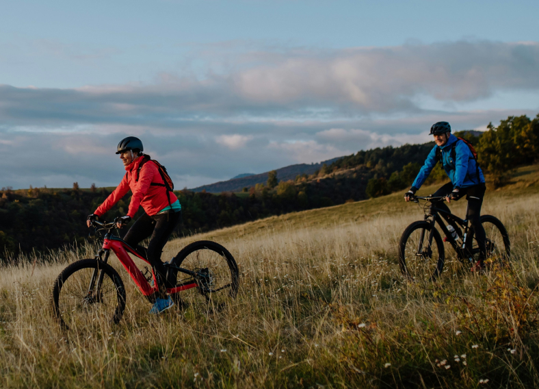 Two people riding e-bikes in a field.