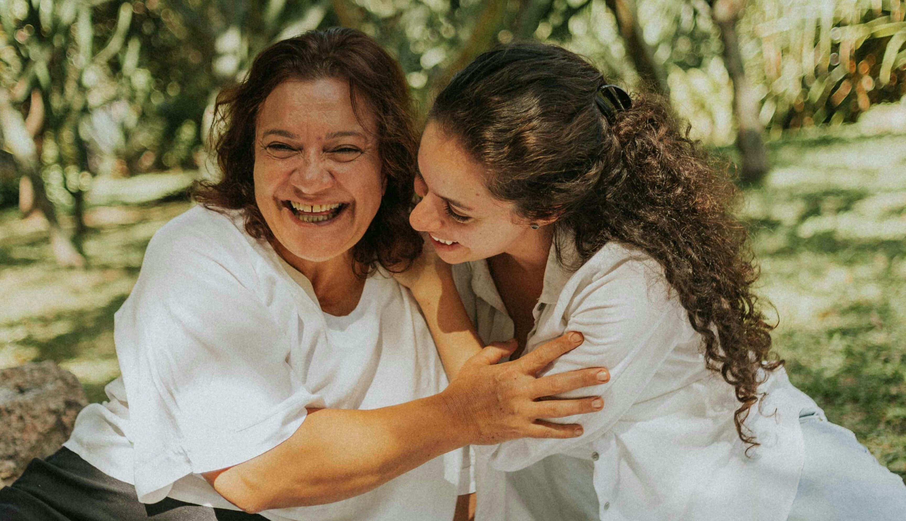 Two women smiling and embracing outdoors, reflecting the human connection and personalized support at the heart of the Onix wellness experience.