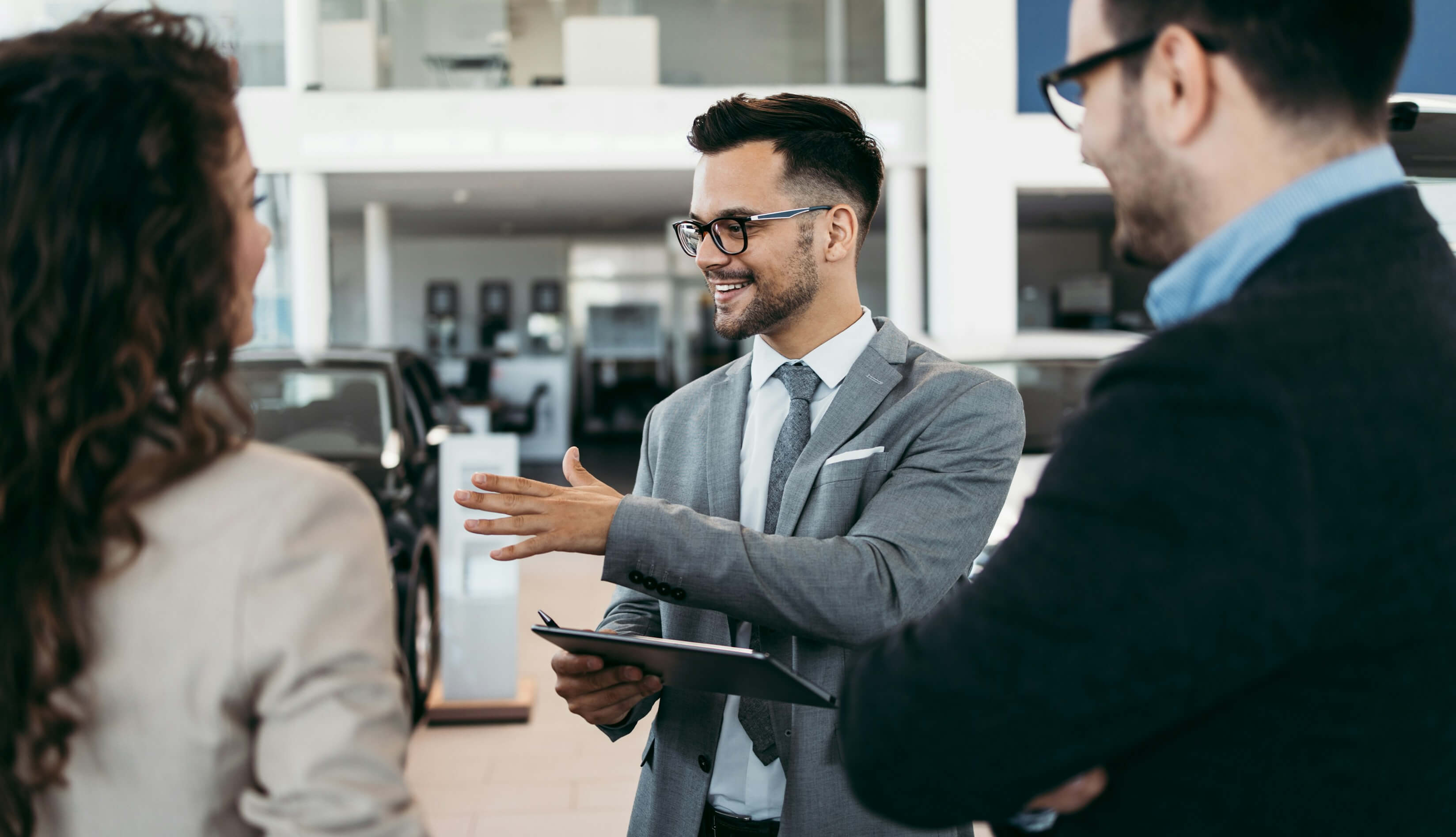 Professionnels de concession automobile interagissant avec un client, illustrant l'accent mis par Neovox sur les véhicules connectés et les relations avec la clientèle.