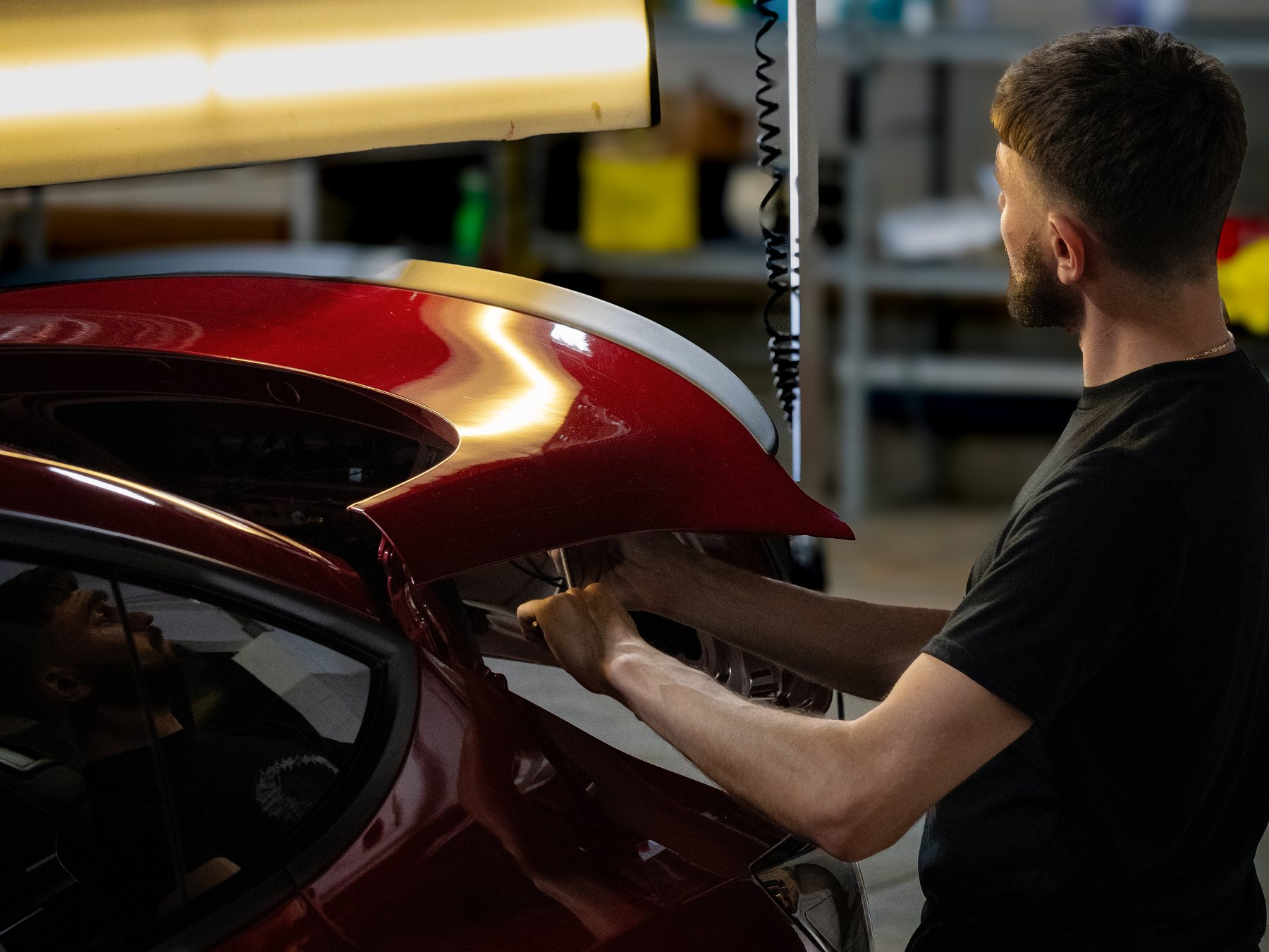 48-Hour technician performing paintless dent repair under the PDR light