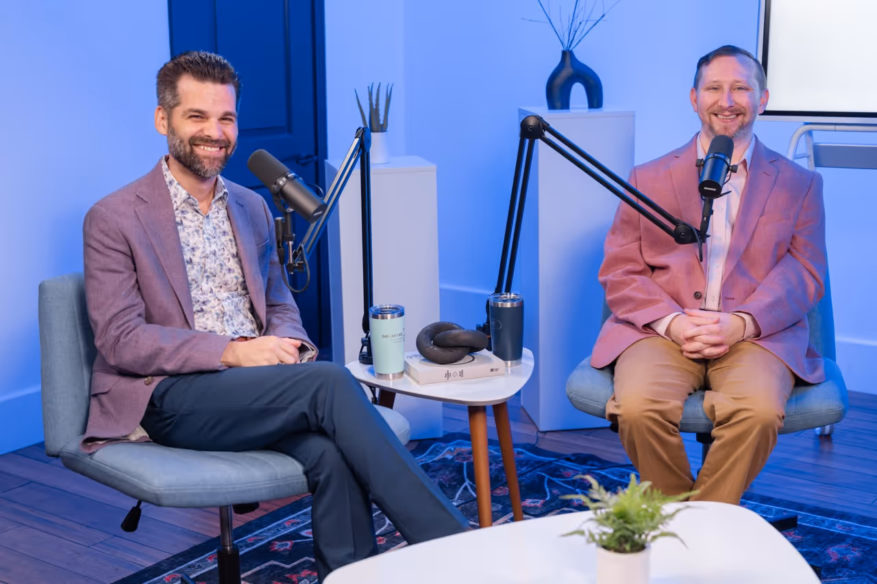 Man and woman in a modern podcast studio, conversing with microphones on adjustable stands