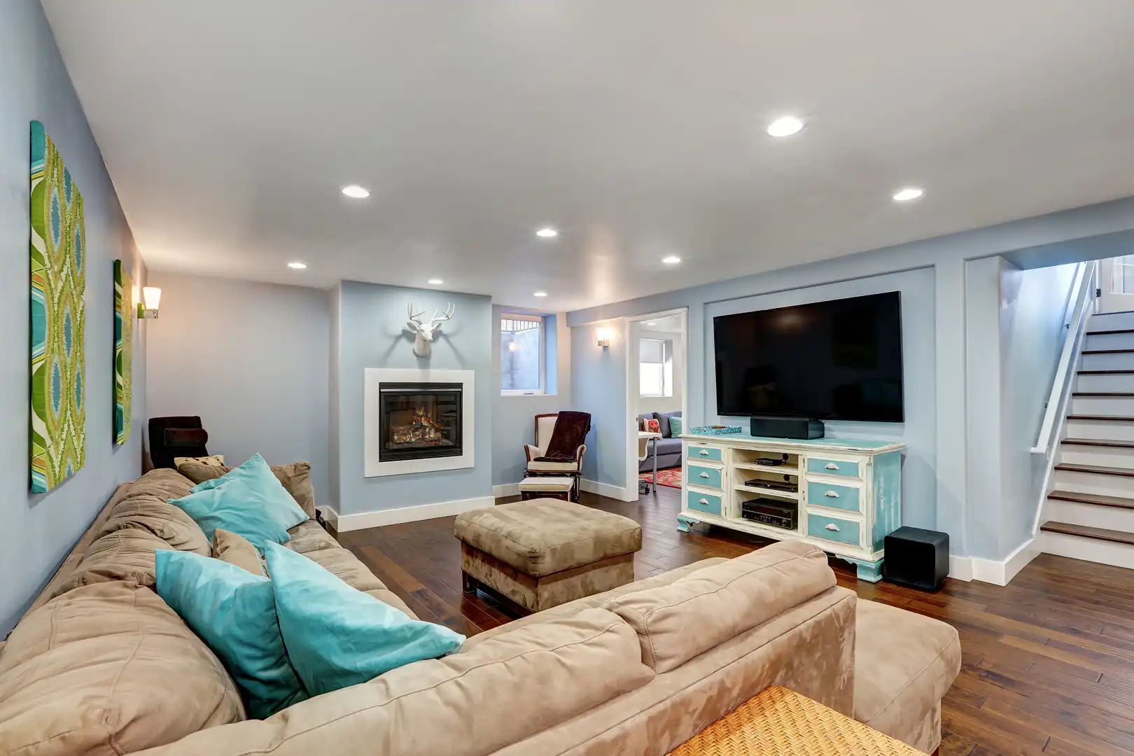 Finished basement remodeling by Callahan & Peters with a living space, fireplace, hardwood floors, and built-in lighting.