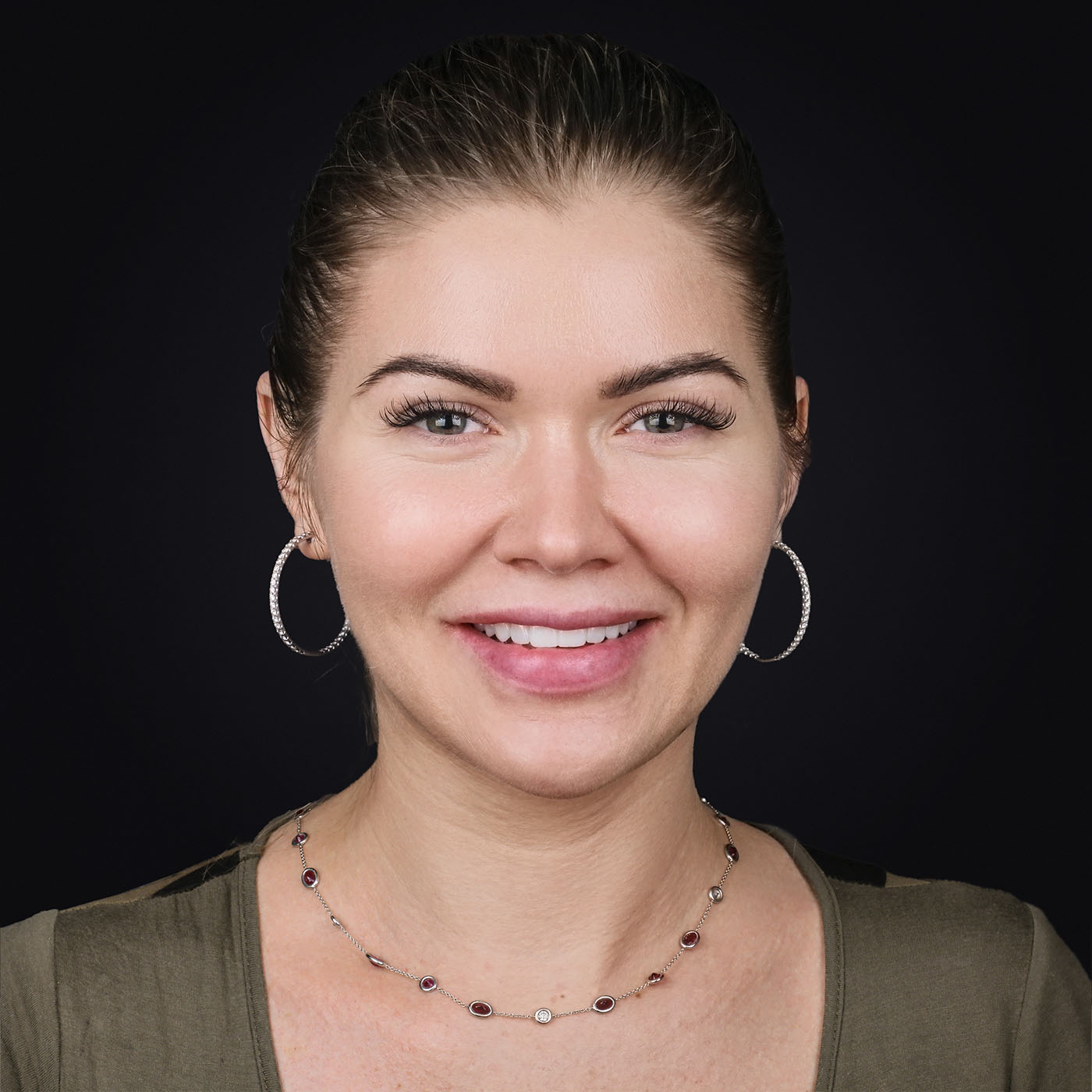 Жінка з сережками, натуральна усмішка – задоволена пацієнтка після реставрації.