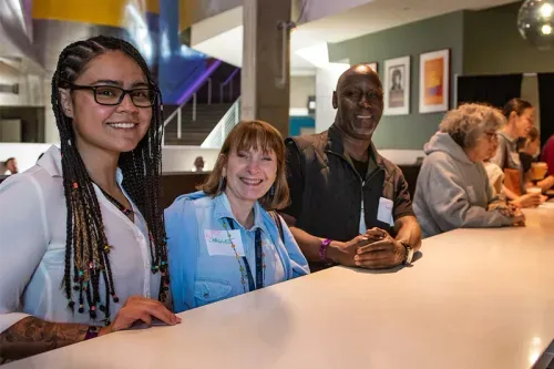 Educators sitting at a counter, one Black woman, one white woman, and one Black man, all smiling