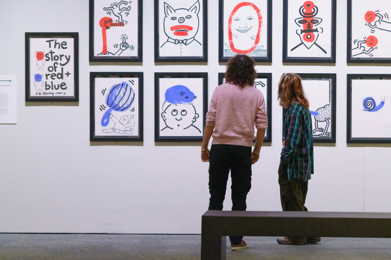 Two visitors looking at drawings in the Keith Haring exhibition