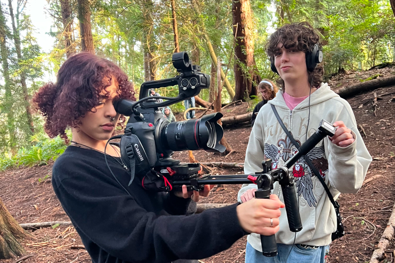 Two teenagers filming in a forest