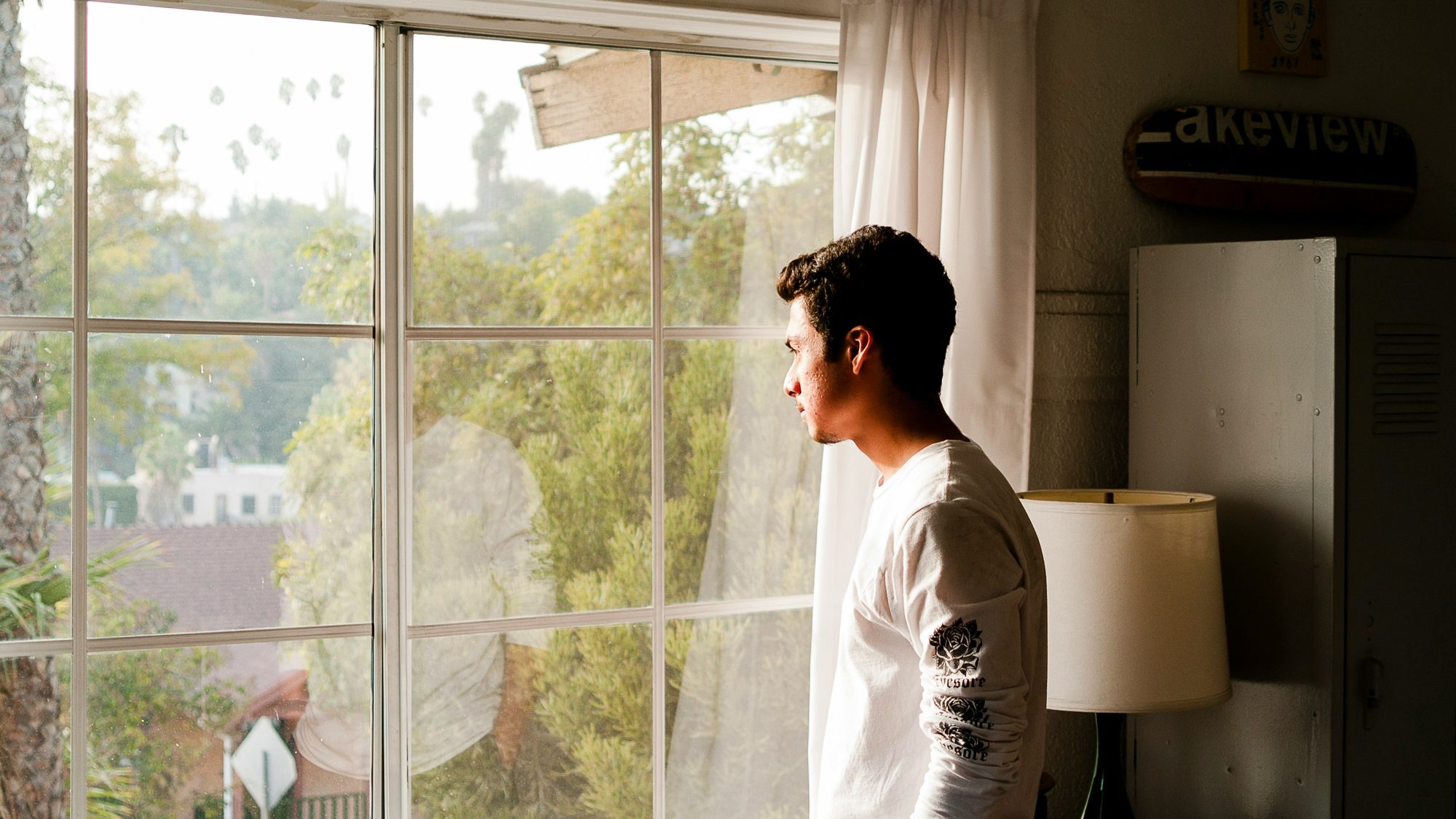 A person standing at a window in soft daylight