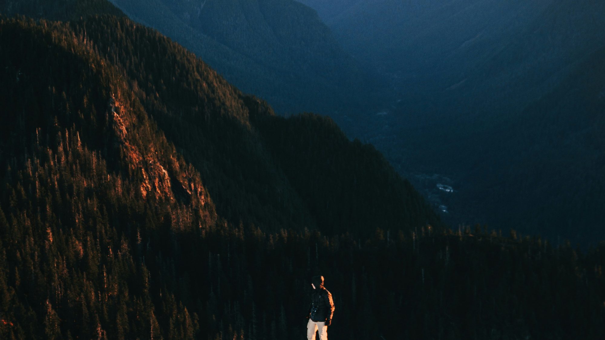 A lone figure on a mountainside beneath a vast ridge