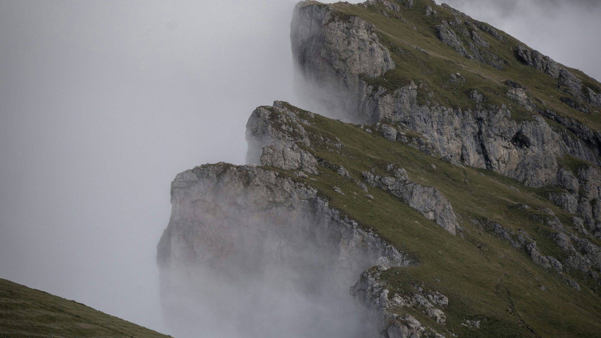 A green mountain ridge disappearing into low cloud