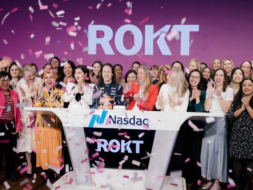 Rokt employees and F1 Academy driver Alisha Palmowski celebrate at the Nasdaq Opening Bell ceremony in New York, surrounded by pink and white confetti, with the Rokt logo displayed on the screen behind them.