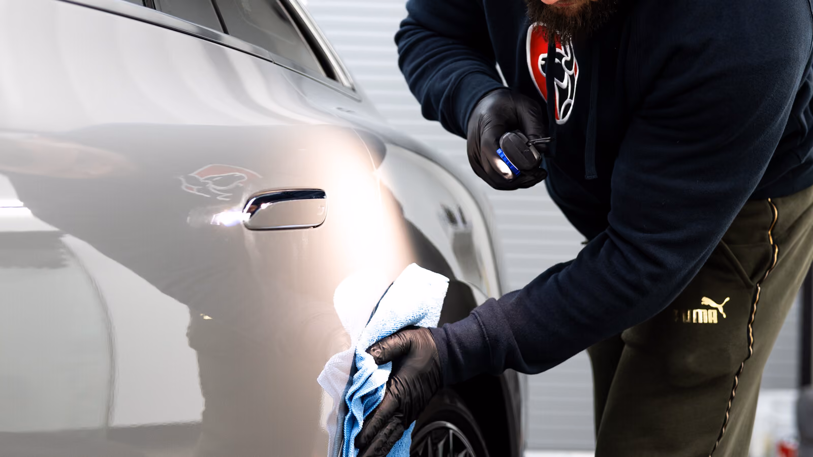 Detailer maintaining a ceramic-coated car with a microfiber cloth at BGI in Sacramento