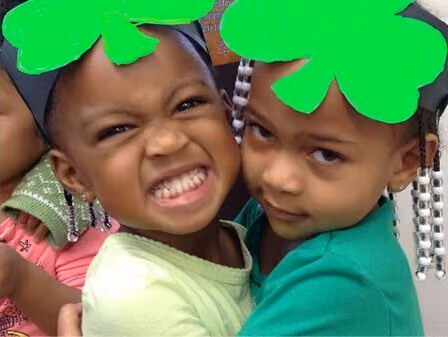 two children with green 4-leaf clover hats on their heads