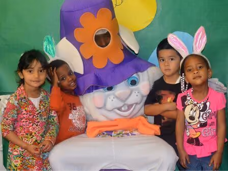 4 kids standing around a big stuffed bunny