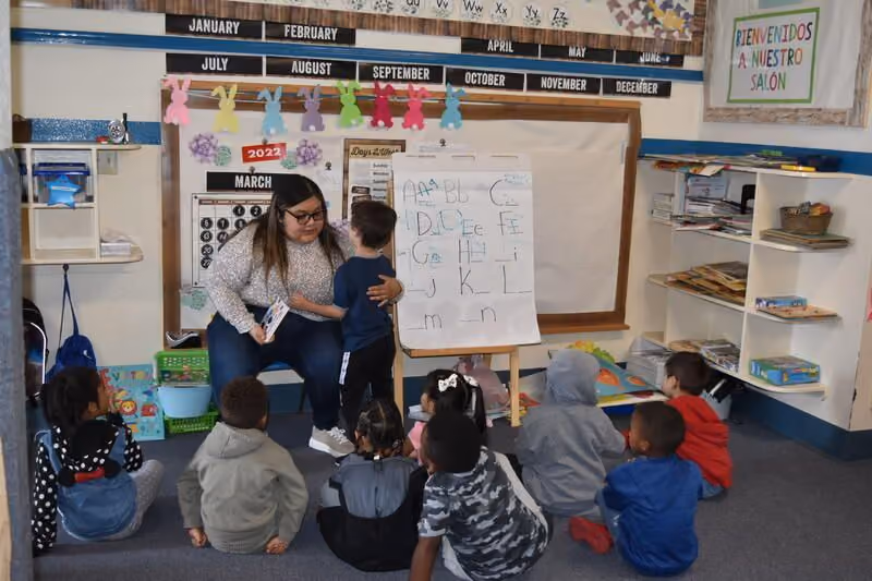 a preschool teacher teach a group of kids who are sitting down 