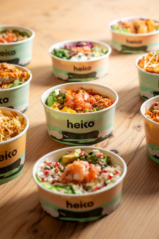 Plusieurs bols Heiko remplis de salades fraîches colorées disposés sur une table en bois.