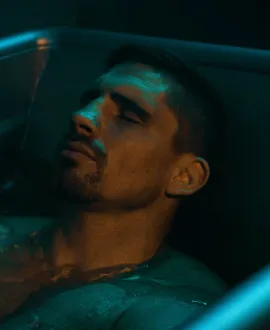 Man med slutna ögon som kopplar av i bath svagt upplyst bath badkar.