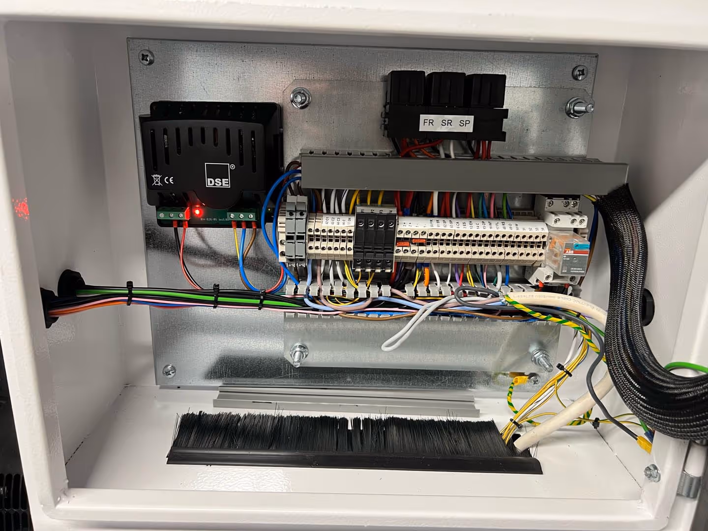An open electrical panel with various wires, switches, and components displayed inside.