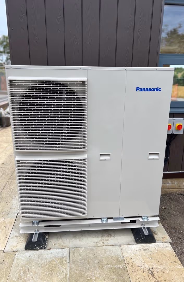 Large outdoor air conditioning unit installed on a concrete patio beside a building.