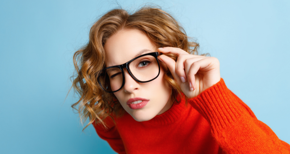 A woman with a red sweater and glasses leans toward the camera holding one side of her glasses with an inquisitive look on her face, wondering "Is a privacy policy required?"