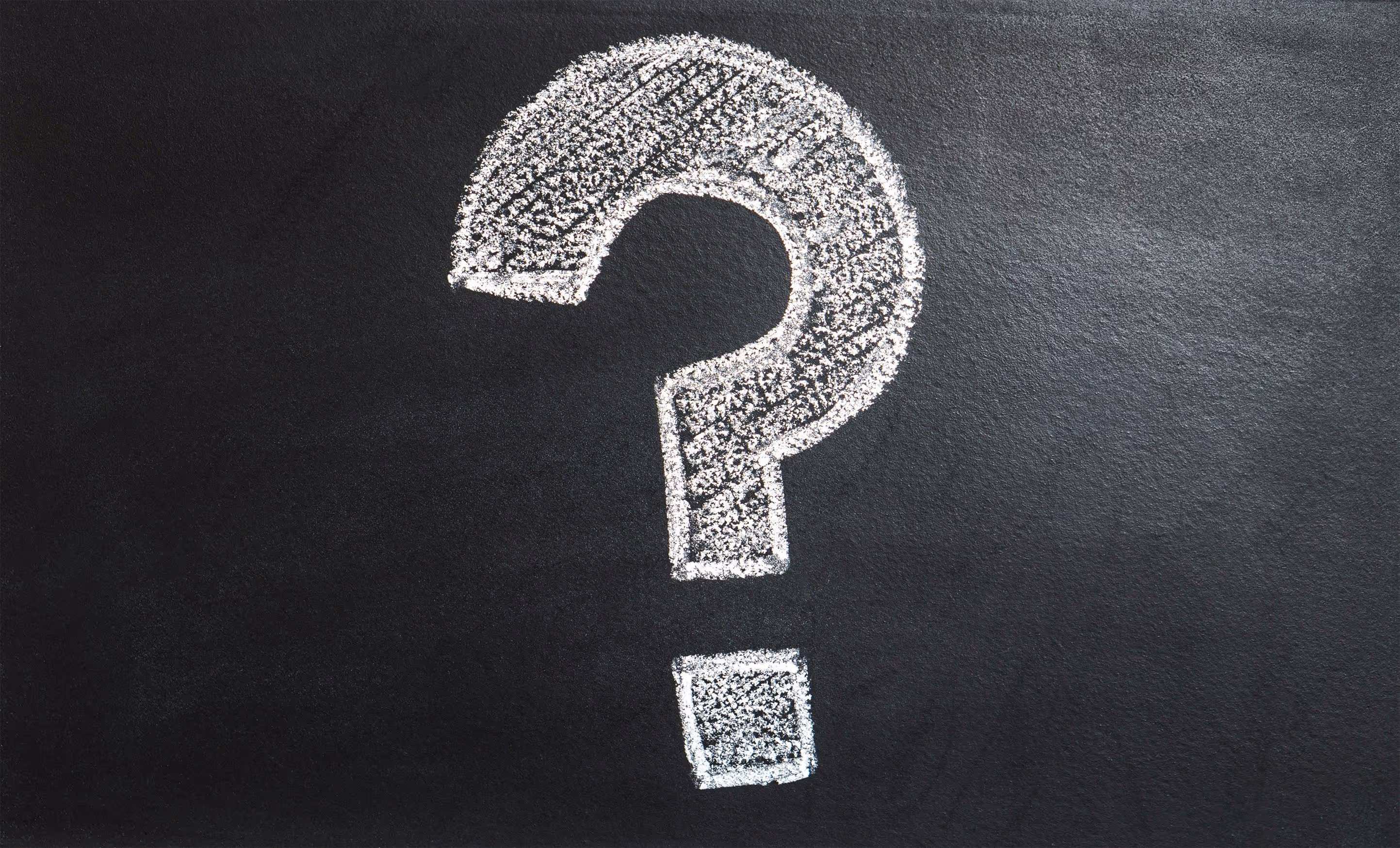 A large question mark drawn in white chalk on a black chalkboard.