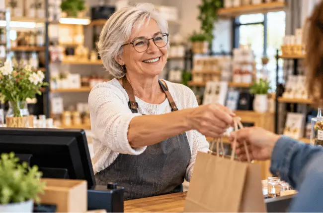 Femme senior souriante travaillant dans une boutique, exemple de cumul emploi-retraite