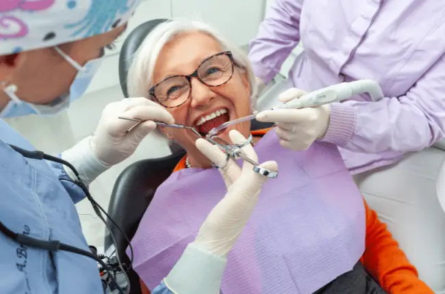 Senior assis dans un fauteuil de dentiste pendant une consultation, soins dentaires moins remboursés par la Sécurité sociale en 2027