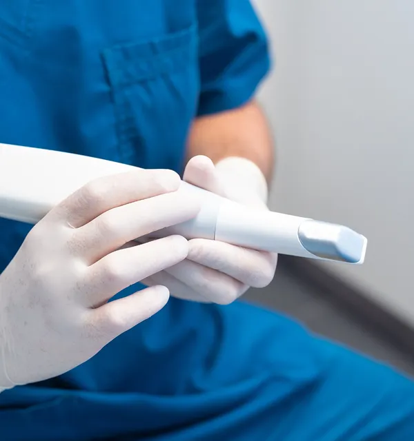 Medical professional in blue scrubs holding a white handheld ultrasound probe.