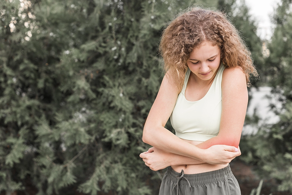Mulher a agarrar o cotovelo esquerdo com dores.