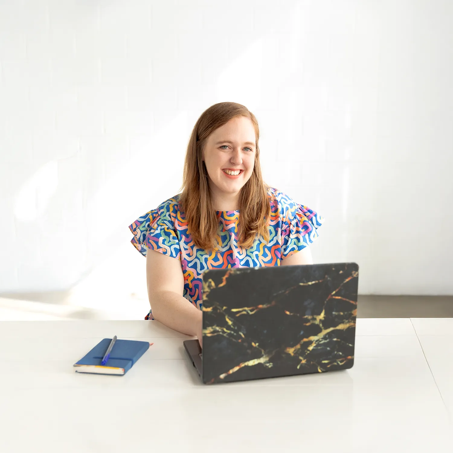 Shannon with her laptop open smiling at the camera