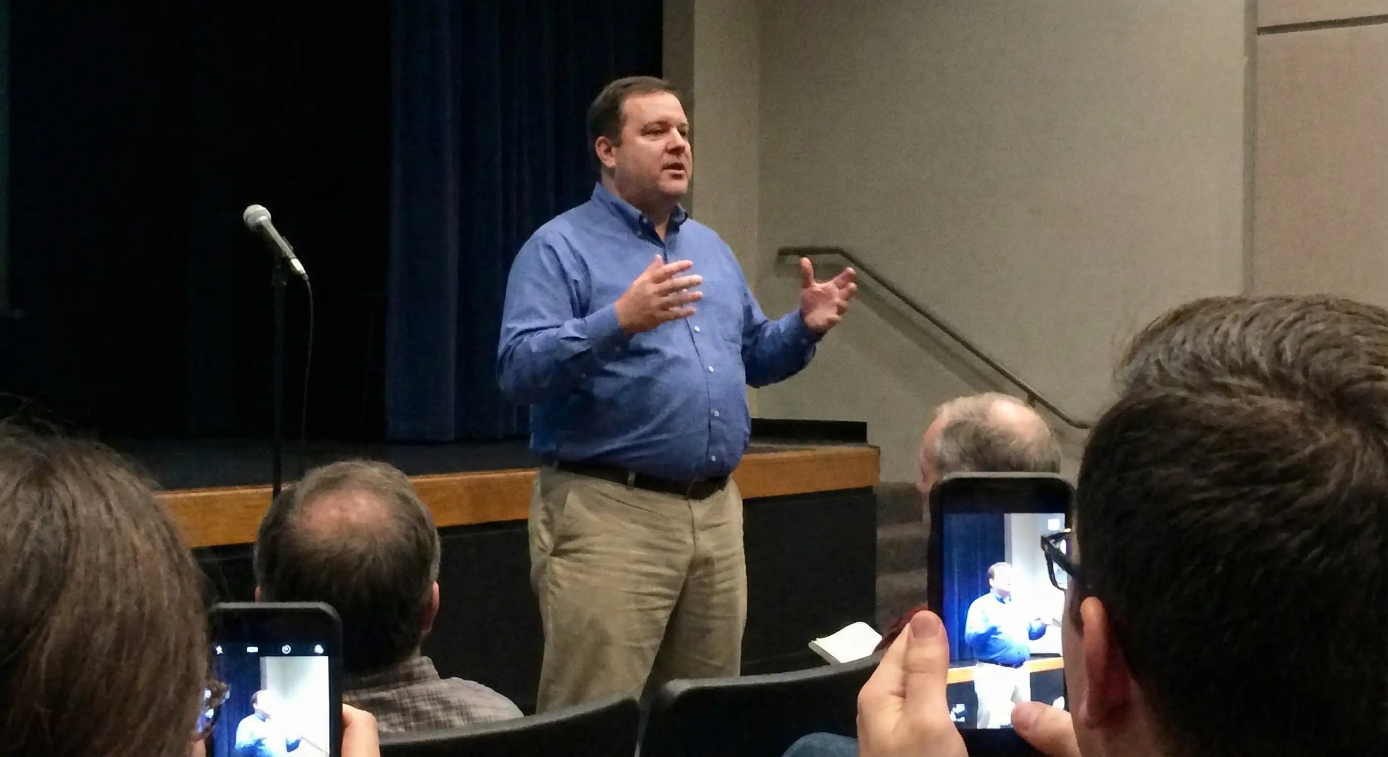 Man speaking to a crowd, choosing not to use the microphone