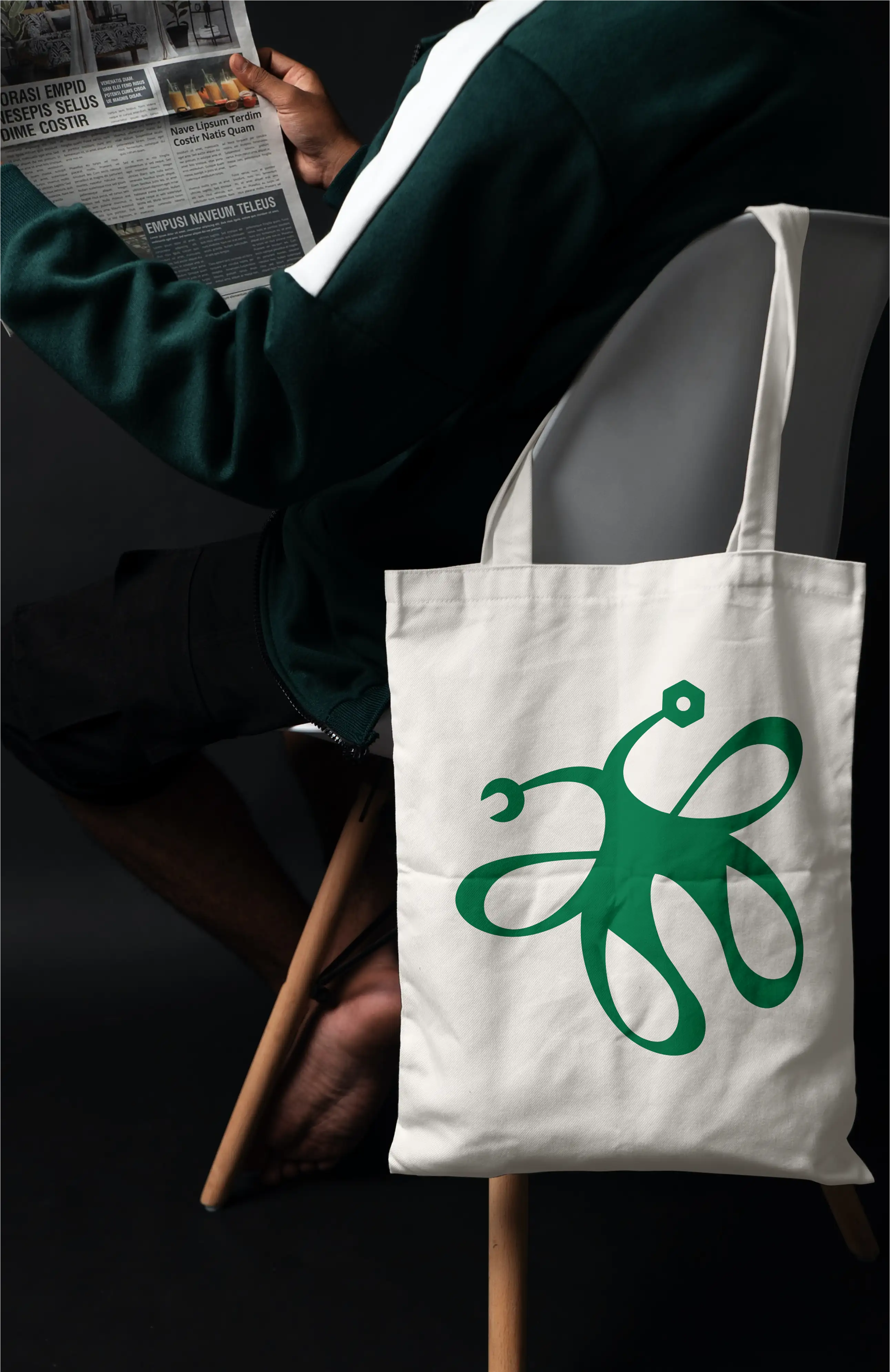A white tote with Enchanted Engineering butterfly mark printed hanging off the back of a chair