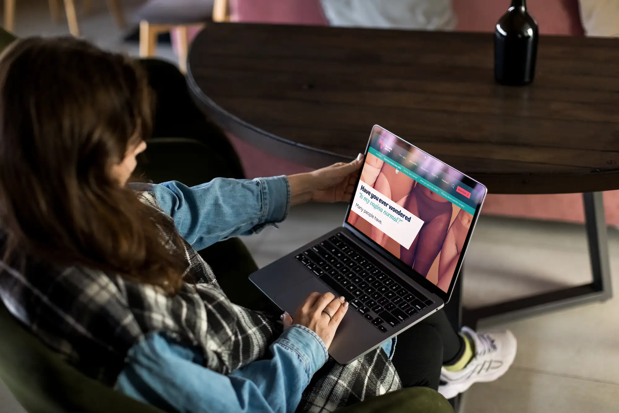 Woman sitting on the couch, looking at the Labia Library homepage.