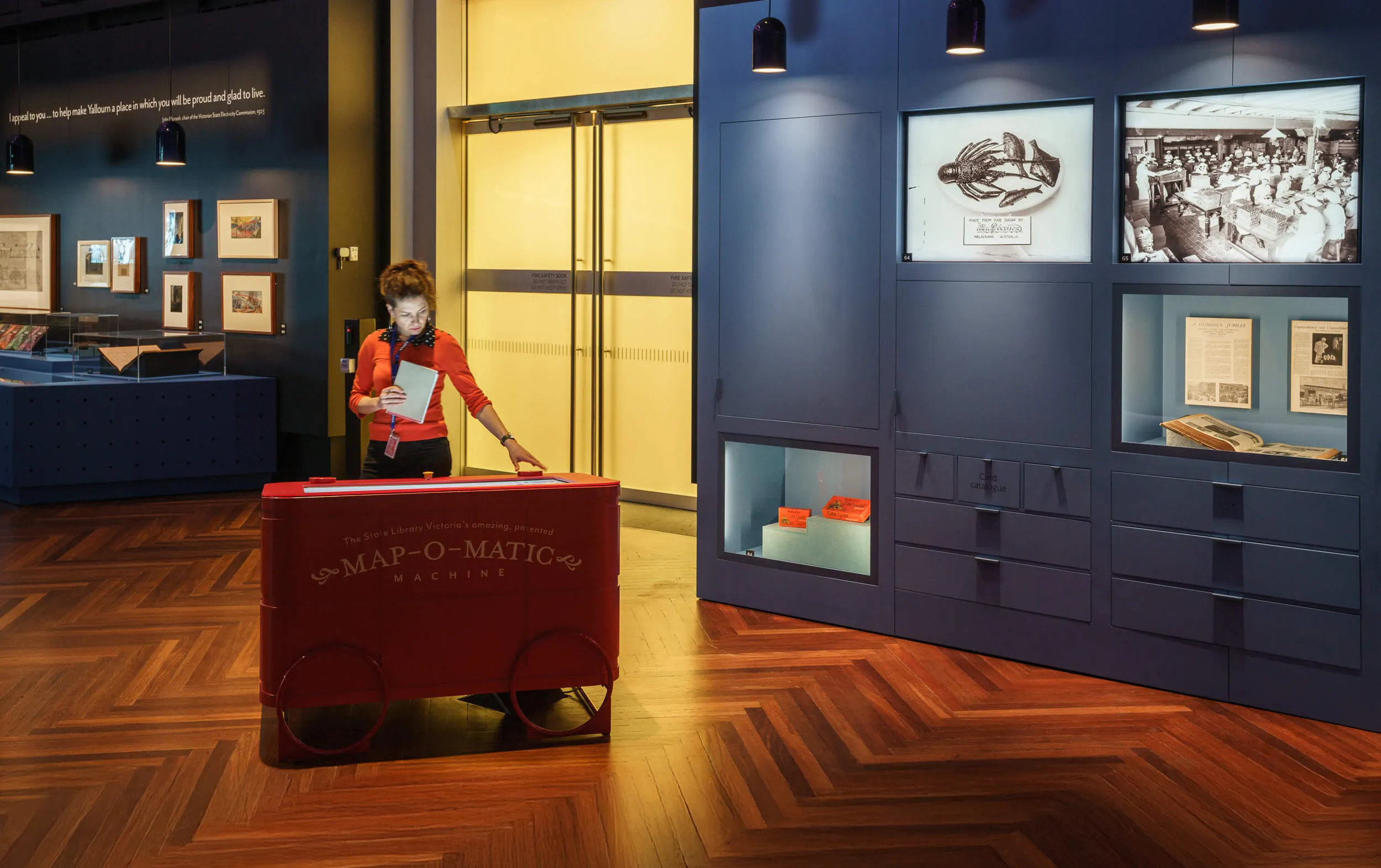 Woman using the bright red Map-O-Matic machine in the gallery.