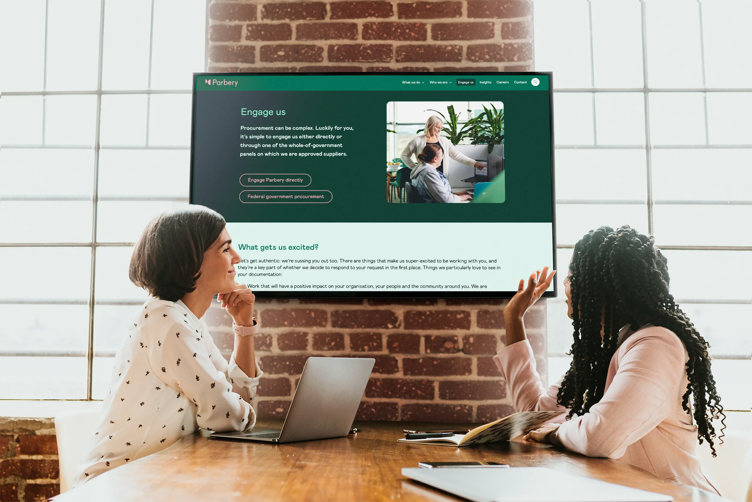 2 staff members in a meeting room looking at Parbery's website on a TV screen
