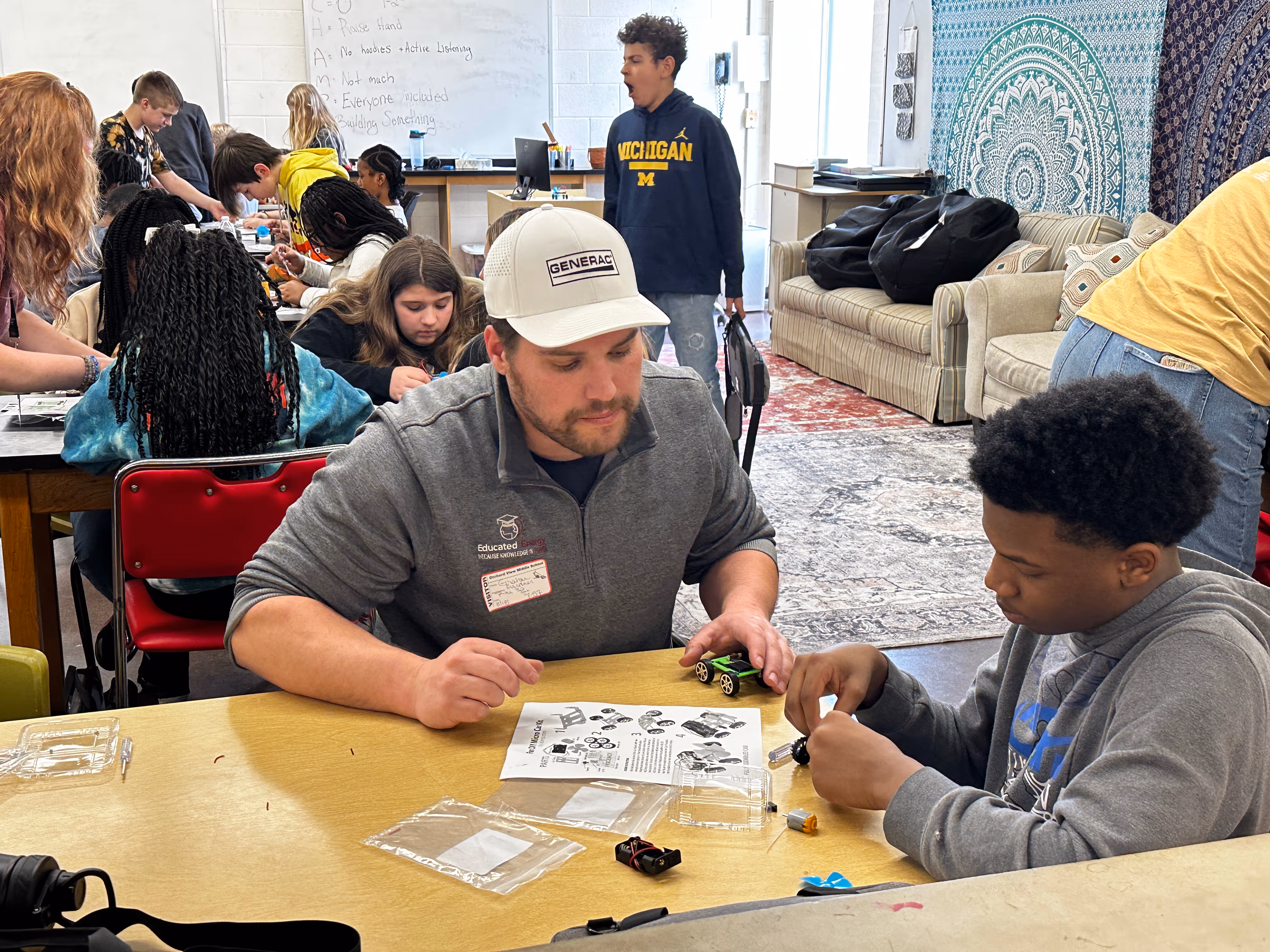 Two people working together at a table with papers and materials in a casual learning environment.