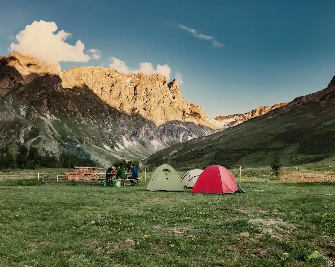 Zelte auf einer Wiese, im Hintergrund die Berge