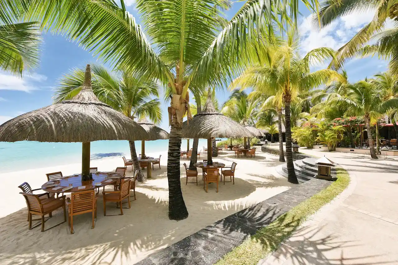 Mauritius: Restaurant-Tische und Stühle am Strand mit Meer und Palmen