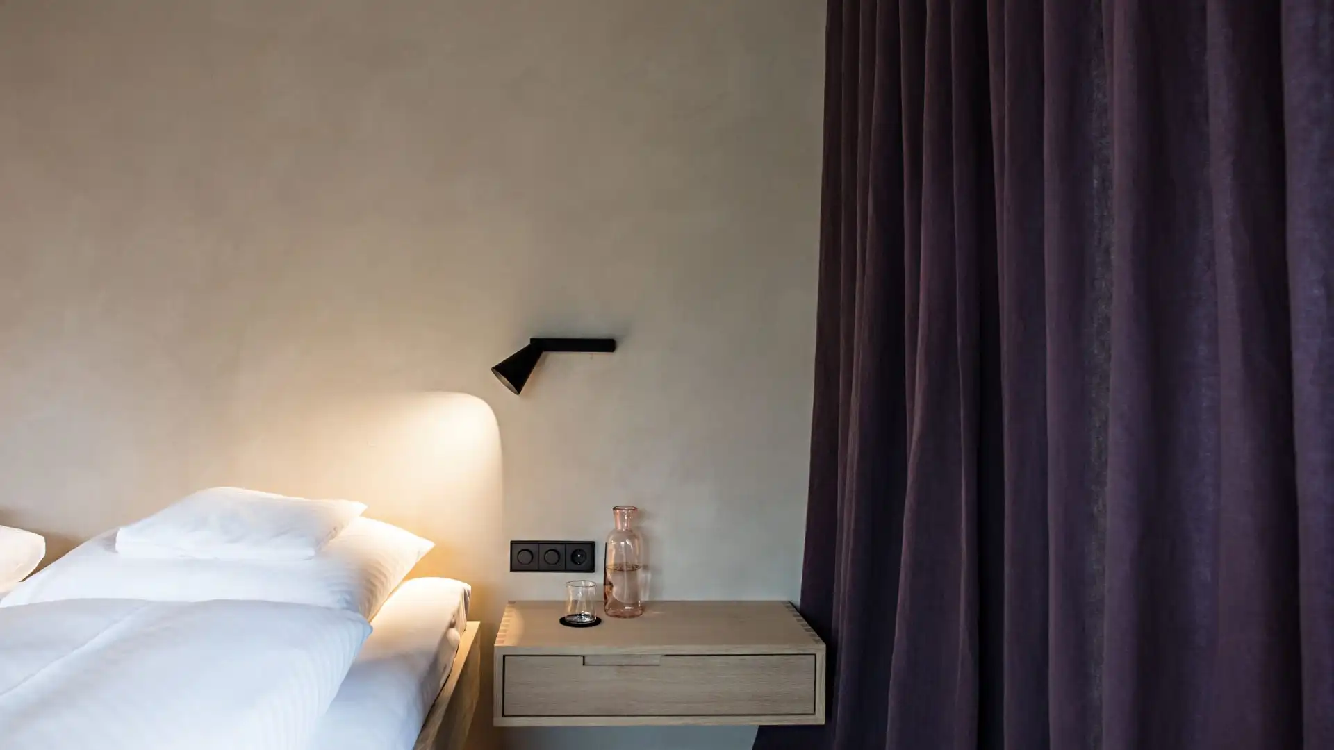 Biohotel Schwanen in Bizau: Schlafzimmer mit beigefarbener Wand und lilafarbenem Vorhang