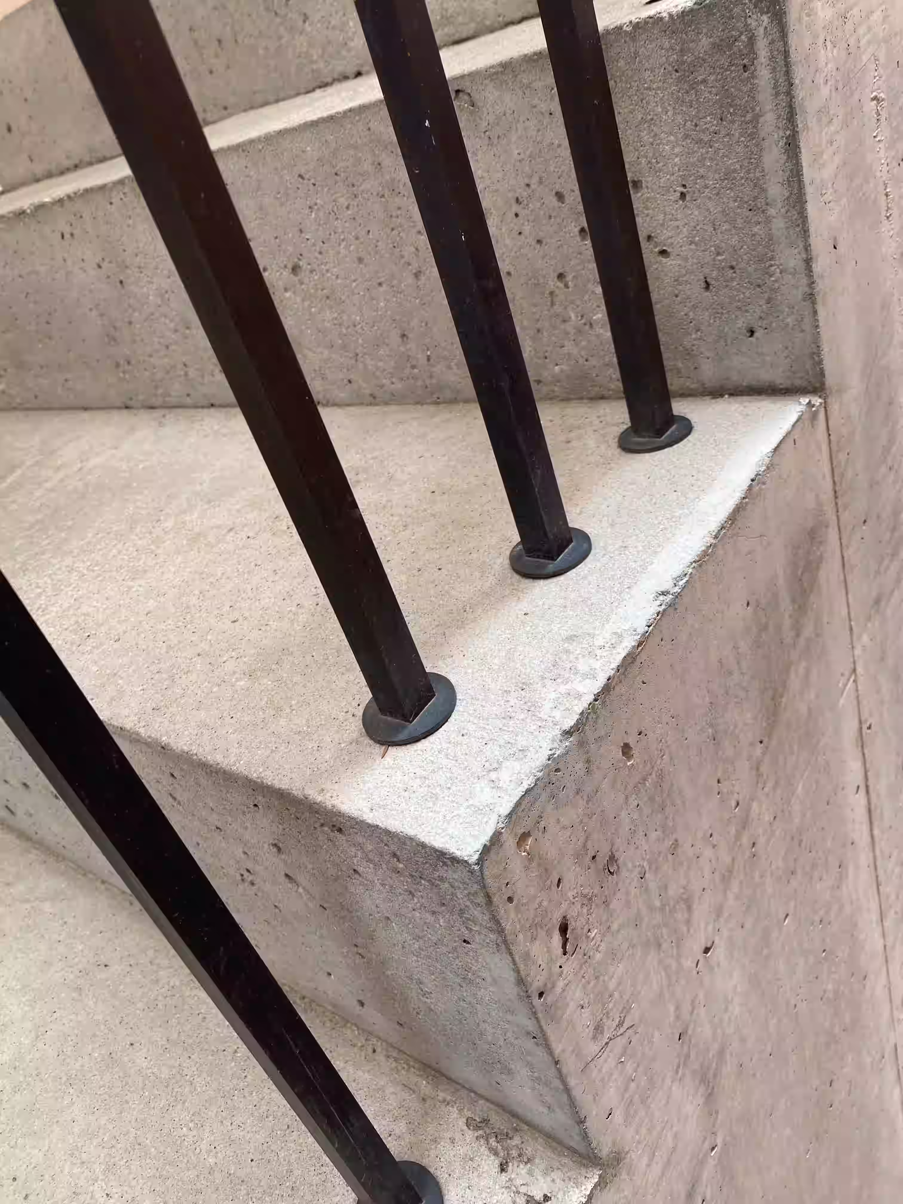 Haus am Turm Sterzing – Betonstufen mit schwarzem Stahlgeländer, Detailaufnahme Außentreppe