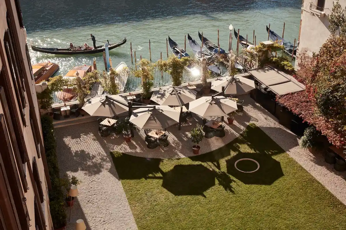 Aman Hotel Venedig - Blick aus dem Fenster auf den Garten, Sonnenschirme von oben und die Lagune mit venezianischen Booten