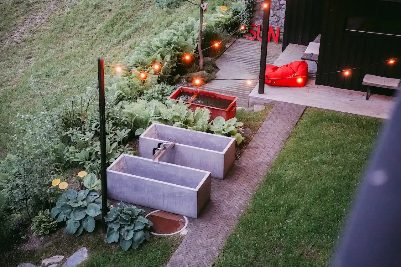 Hotel Seebichl Kitzbühel: Outdoor Badewannen aus Beton und Sonnendeck in Hotelgarten