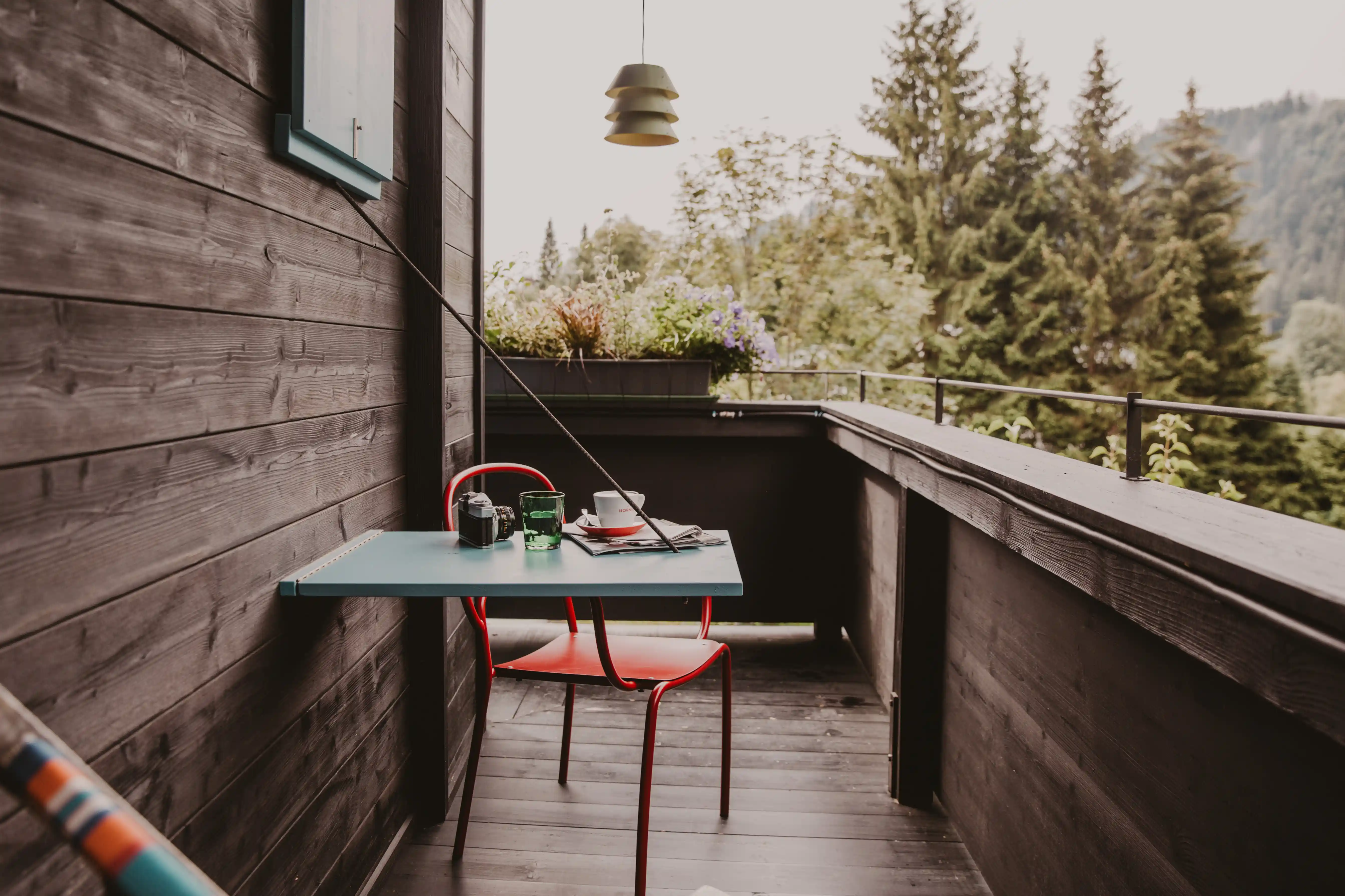 Holzbalkon im Hotel Seebichl: Ein Tisch, ein Stuhl, ein Kaffee, eine Zeitung und Blick auf den Wald