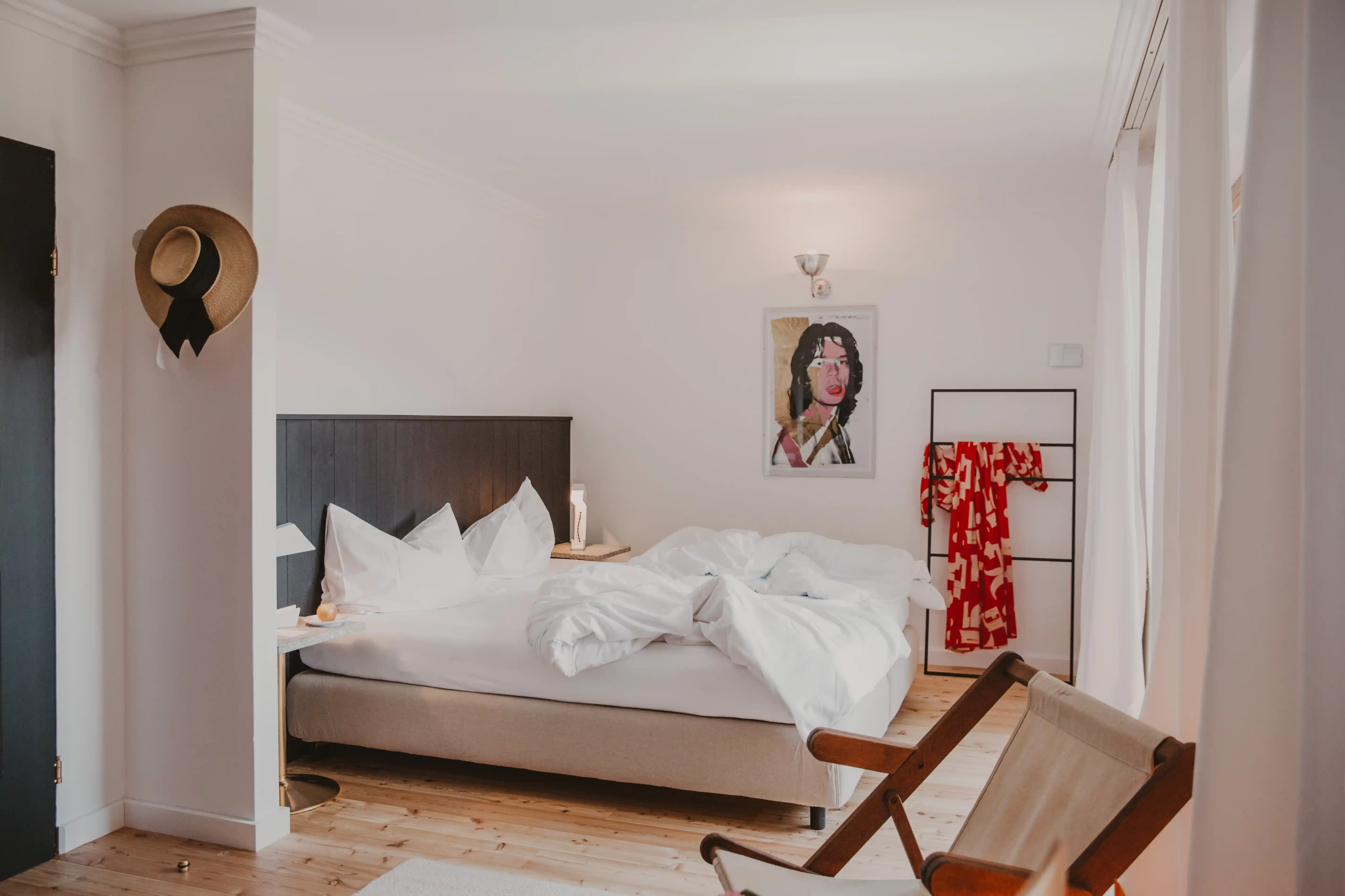 Erholsamer Schlaf: Doppelzimmer im Hotel Seebichl: Weiße Laken, grauer Bettkopf, Holzstuhl, weiß gestrichene Wand