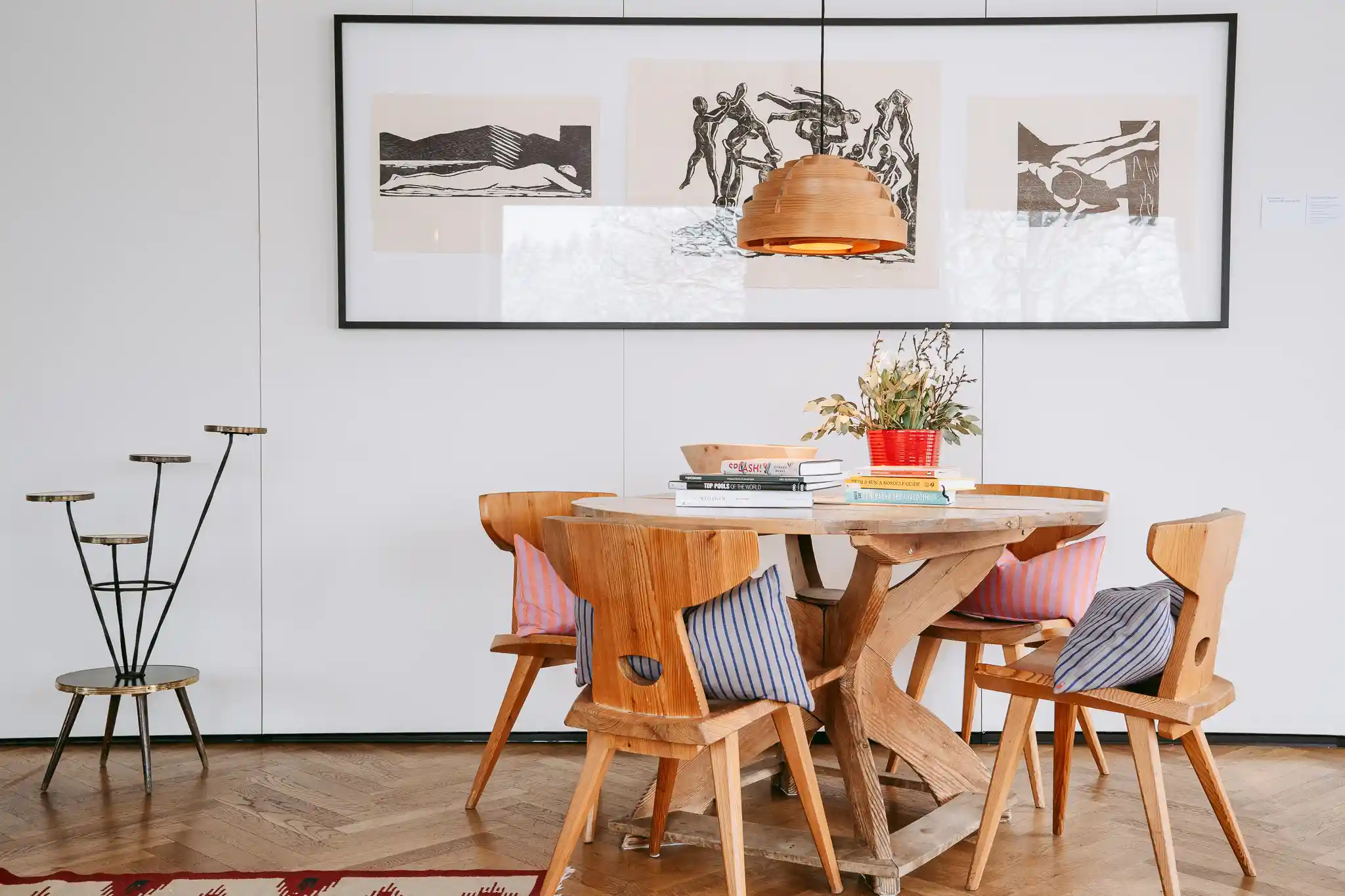 Holztisch mit vier Holzstühlen auf altem Parkettboden, an der Wand drei schwarz-weiß Kunstdrucke. Sitzecke im Hotel Seebichl