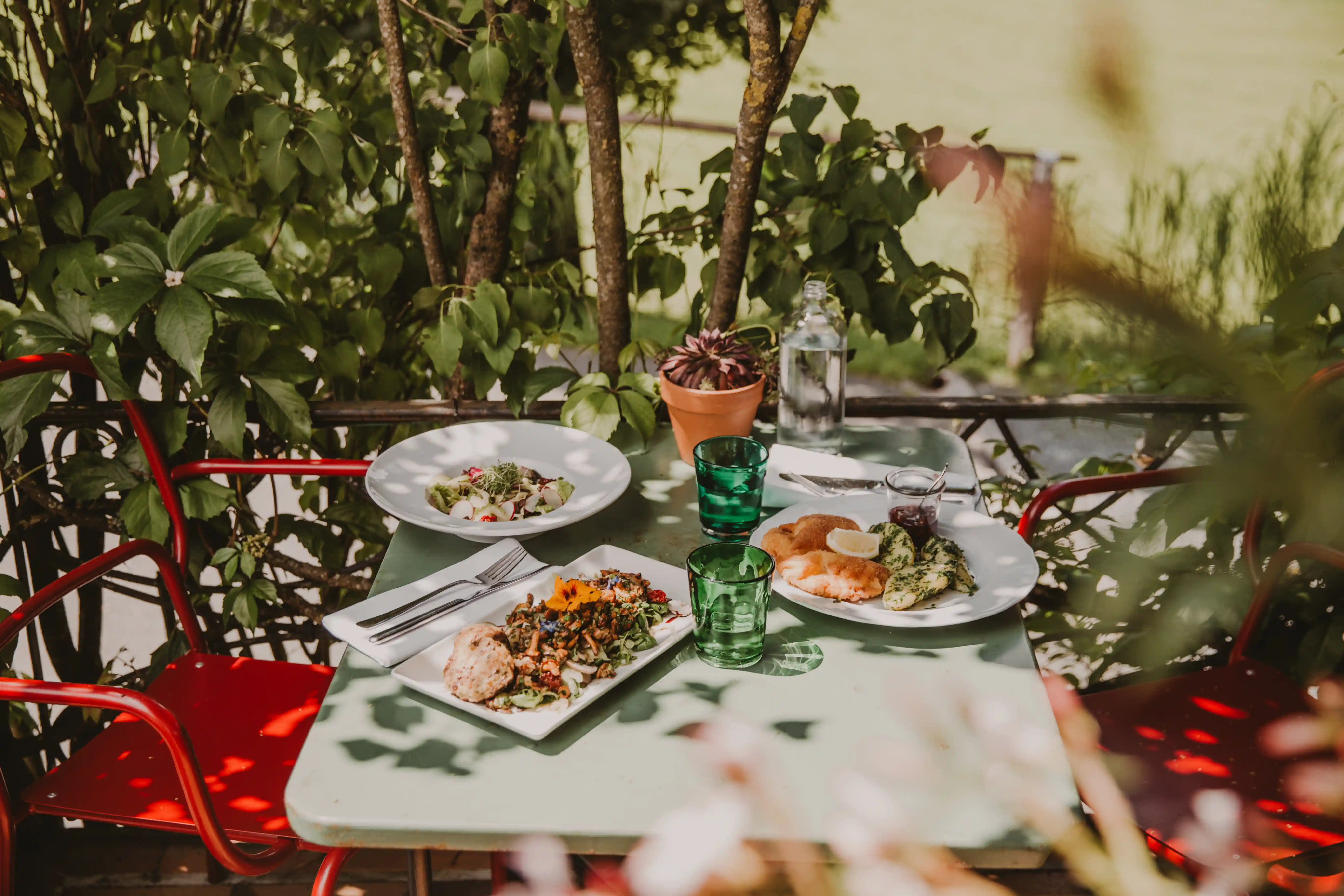 Gedeckter Tisch auf dem Außenbalkon mit verschiedenen Gerichten. Darunter Schnitzel und Salat mit Pfifferlingen. Alles aus der Küche im Hotel Seebichl bei Kitzbühel
