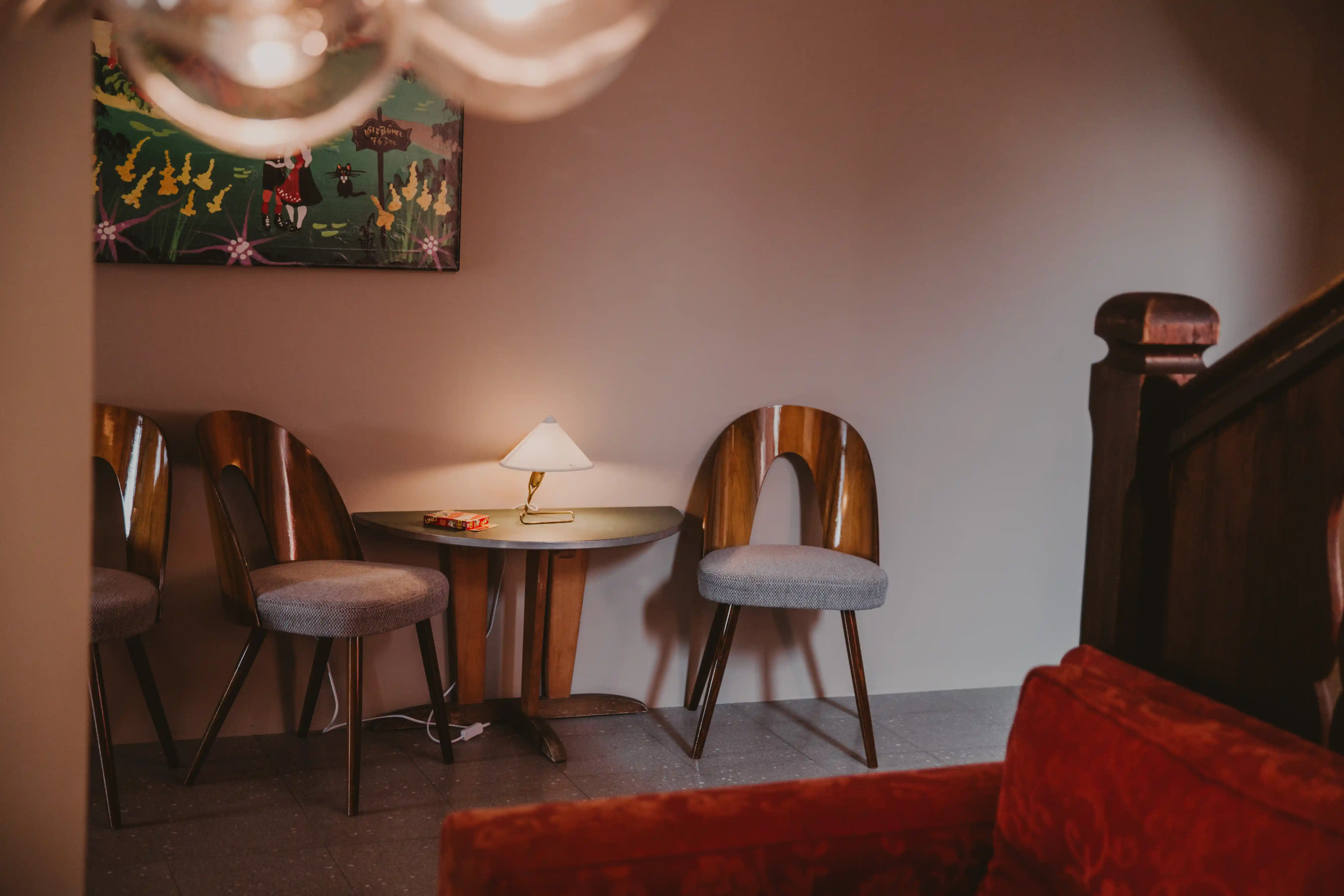 60er Jahre Sitzbereich im Hotel Seebichl: Zwei alte Stühle, ein kleiner Tisch an der Wand, im Vordergrund ein Anschnitt von einem roten Sofa aus Samt